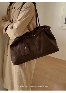 Detailed view of deep brown vintage tote bag with detachable pouch on a stylish model