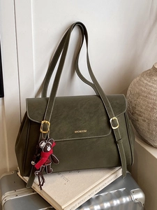 Olive green faux leather tote bag with gold logo and bear charm on silver suitcase