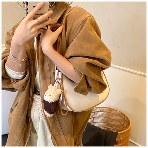 Mirror selfie showing a white leather hobo bag with a cute brown teddy bear charm