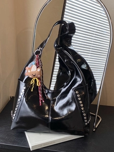 Large black glossy patent leather tote bag with silver rivets and bear charm