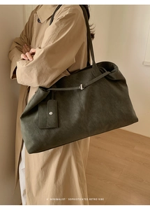 Close-up of moss green suede tote bag featuring a metallic buckle and mini charm pouch