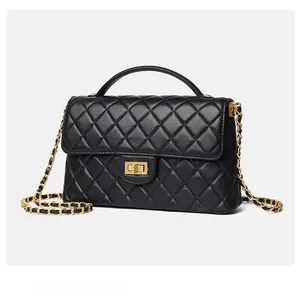 Detailed view of the quilted black leather handbag with gold metal clasp and chain strap