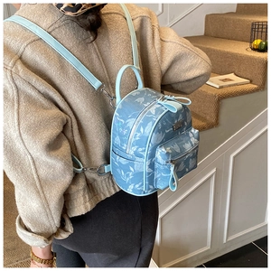 Close-up of light blue floral mini backpack with white flower patterns and adjustable straps