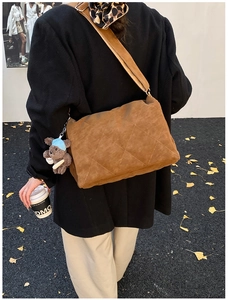 Quilted brown suede crossbody bag with teddy bear charm on model in autumn setting