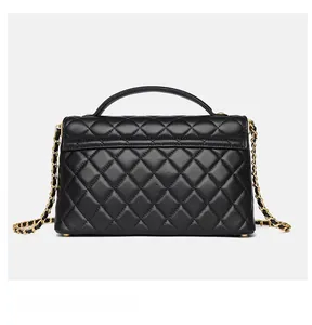Close-up of quilted black leather texture and gold chain strap on small square crossbody bag