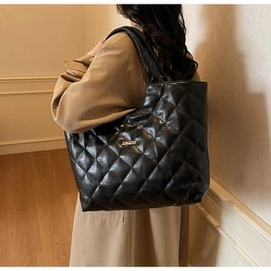 Gros plan d'un sac cabas en cuir matelassé noir avec logo en métal doré et losanges