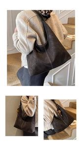Detail view of large dark brown matte tote bag with white stitching and flower tassel