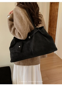 Detail of a large black vintage tote bag with a matching small hanging pouch on a shoulder