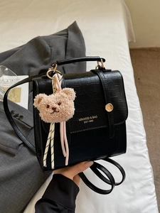 Elegante borsa nera a motivo coccodrillo con fibbia dorata e ciondolo a orsetto