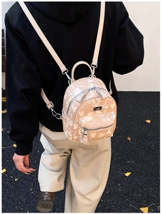 Detail of a mini floral beige backpack worn by a model in an outdoor urban setting