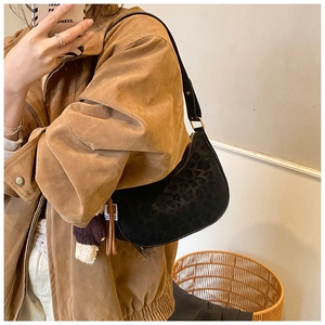 Close-up of black leopard print crescent bag with plush pendant in mirror selfie view