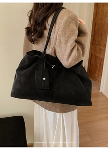 Detail of large black matte tote bag with shoulder strap and side storage pouch