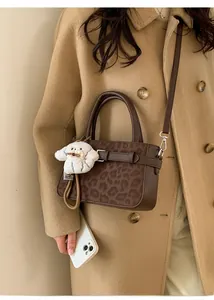 Détail d'un sac à main léopard marron avec un charm chiot en peluche et bandoulière