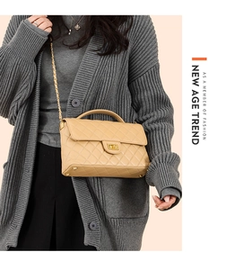 Detail of trendy quilted beige crossbody bag with metal chain strap and twist lock closure