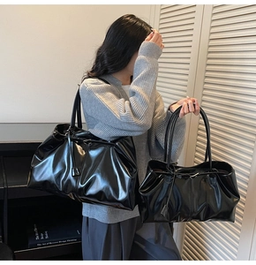 Detail of glossy black leather tote bags in large and small sizes with slim straps
