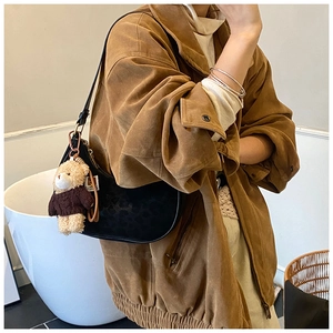 Detailed view of black leopard print crescent bag with cute bear charm worn by a model