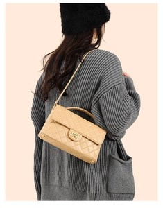 Detail of quilted leather crossbody bag with chain strap shown on model shoulder
