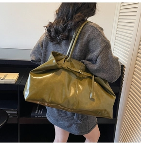 Olive green high-gloss faux leather tote bag shown in a professional work setting