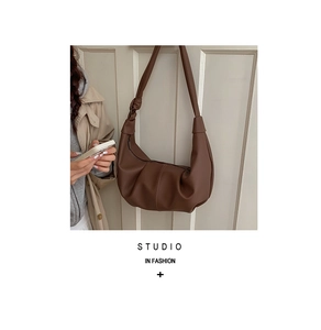 Detail of a brown pleated hobo bag with unique knotted strap and soft PU leather texture