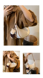 Detail showing white crescent shoulder bag with brown trim and cute plush bear charm