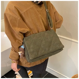 Detail of army green quilted crossbody bag with matte texture and bear charm accessory