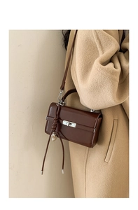Detail of dark brown wax leather kelly bag with silver turn-lock and woven knot charm