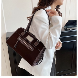 Detail of a dark brown shoulder bag with white contrast stitching and silver zipper pocket