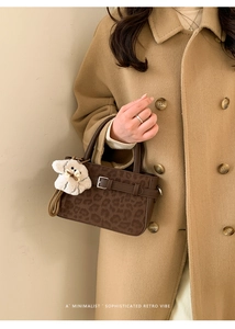 Détail d'un sac à main léopard avec charm peluche porté sur un manteau d'hiver