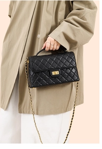 Detailed view of black quilted leather bag with gold clasp and chain strap