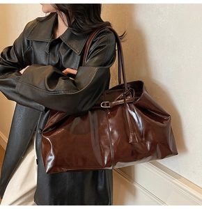 Detail of vintage coffee brown oil-wax leather tote with glossy finish and metal buckles