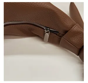 Detail of silver metal zipper and textured brown lychee leather on a shoulder bag