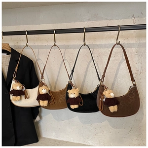 Detail view of four crescent-shaped leather underarm bags with cute plush bear charms