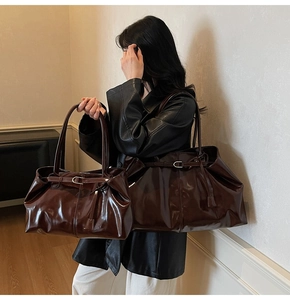 Detail view of dark brown glossy leather tote bags in two sizes with sleek shoulder straps