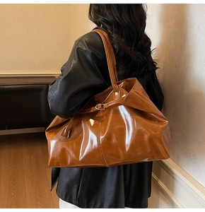 Macro view of polished caramel brown leather texture and side strap detail of the tote bag