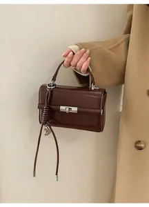 Close-up of dark brown leather handbag with silver twist lock and knot handle charm