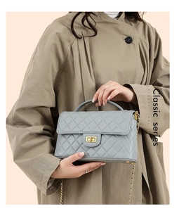Close-up of light grey quilted handbag featuring gold twist lock and chain strap detail