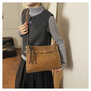 Dettaglio borsa tote in pelle opaca marrone con chiusura a scatto in metallo e nappa