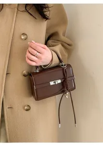 Detail of dark brown lychee textured PU leather shoulder strap with silver metal buckle