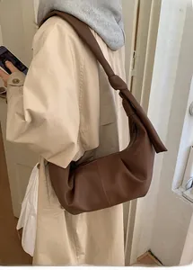 Detail of knotted shoulder strap and pebbled leather texture on dark brown slouchy hobo bag