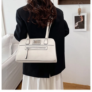 Detail of white PU tote bag showing black contrast edges and silver metal nameplate