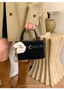 Détail du sac léopard avec boucle en métal et breloque chiot dans un style rétro chic