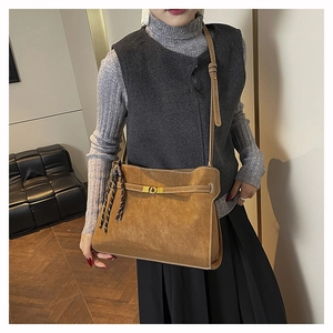 Dettaglio della borsa tote in pelle scamosciata caramello con fibbia oro e manico intrecciato