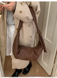 Detail of a brown leather hobo bag featuring soft pleats and a stylish knotted shoulder strap