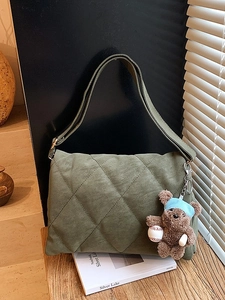 Quilted olive green shoulder bag with a cute bear charm in a vintage lifestyle setting