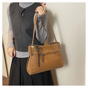 Dettaglio borsa tote in pelle marrone opaca con chiusura a scatto e nappa intrecciata
