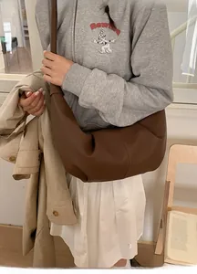 Detail of a large coffee-brown hobo bag with stitched texture on a soft interior setting