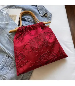 Detailed shot of red jacquard handbag with natural bamboo handle and floral patterns
