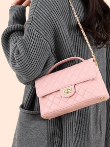 Pink quilted leather crossbody bag with gold chain strap worn by a model in a grey sweater