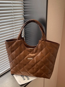 Sac cabas matelassé marron avec motif à losanges et logo en métal sous le soleil