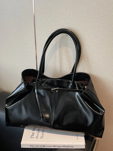 Large black tote bag in glossy leather finish with minimalist straps and metal buckle